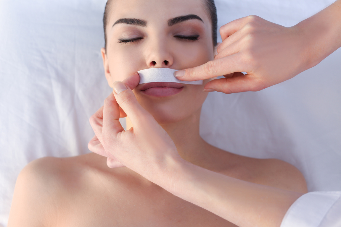 Beautician Depilating  Woman's Face with Wax in Spa Center
