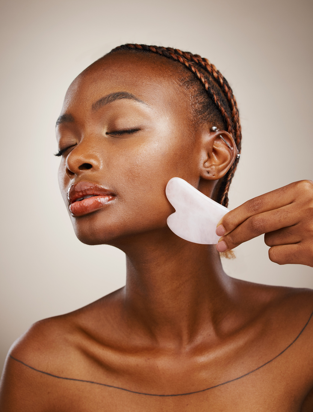 Woman, Beauty and Gua Sha for Face Massage, Aesthetic Skincare and anti Aging Dermatology in Studio on Grey Background. African Model, Crystal Stone Tools or Lymphatic Drainage with Facial Cosmetics